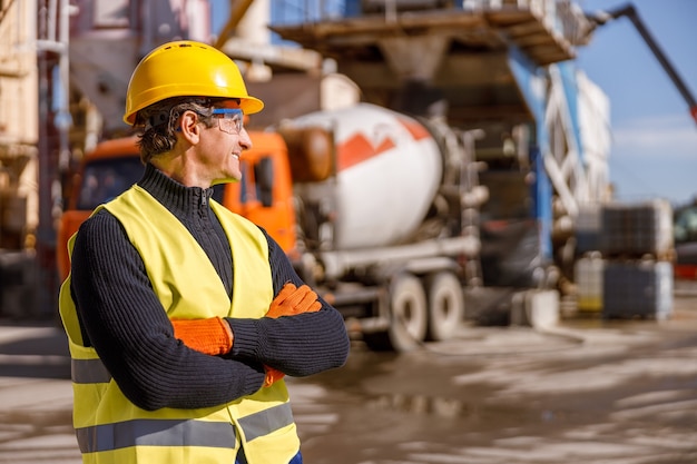 Fröhlicher männlicher Ingenieur, der draußen am Industriestandort steht