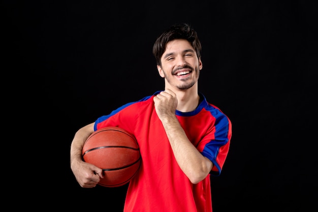 Fröhlicher männlicher Spieler mit Basketball auf Schwarz