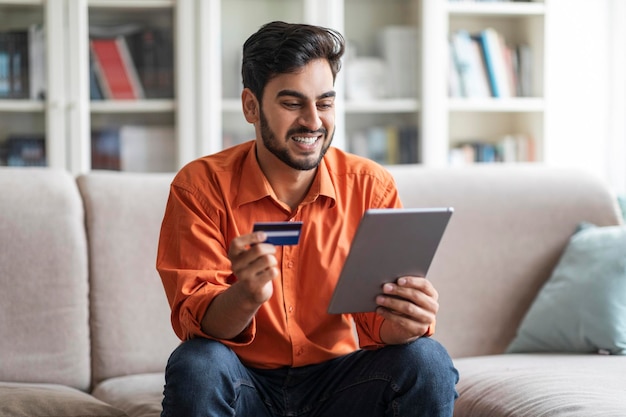 Fröhlicher Mann aus dem Nahen Osten bestellt Essen online mit einem digitalen Pad