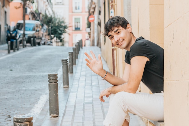 Fröhlicher Mann, der draußen an der Kamera mit Kopienraum grüßt. Stadt Madrid. Glückliches Lebensstilkonzept. Glücklich mit neuen Gewohnheiten