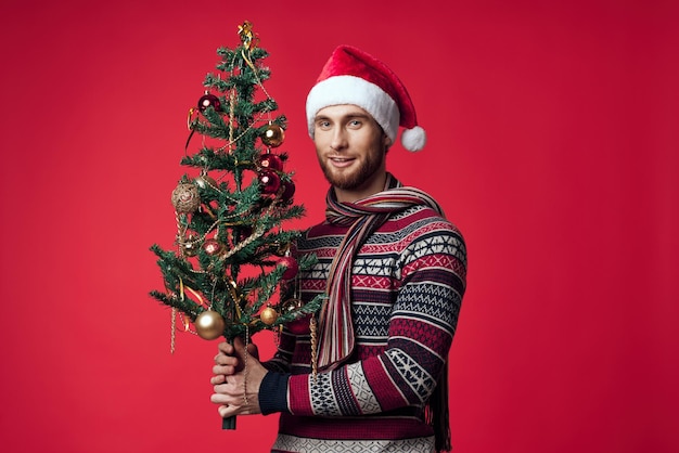 Fröhlicher Mann in einem Weihnachtsmannshut Weihnachtendekorationen Urlaub Neujahr roter Hintergrund Hochwertiges Foto