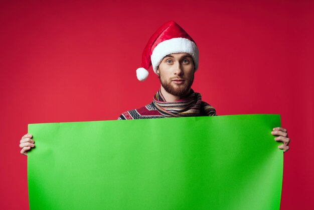 Fröhlicher Mann in einer Weihnachtsmütze, der einen isolierten Hintergrund mit Bannerfeiertag hält