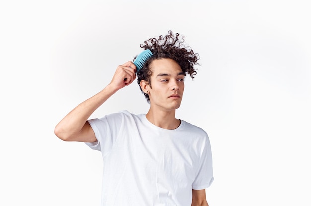 Fröhlicher Mann in weißem T-Shirt, Kamm, Haare, Locken, Emotionen, Hochqualitätsfoto