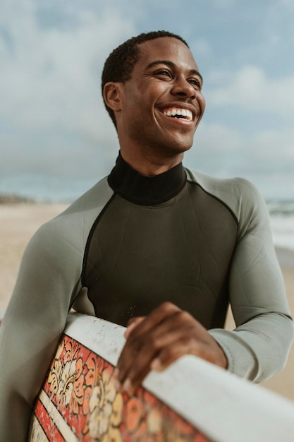 Fröhlicher Mann mit Surfbrett am Strand