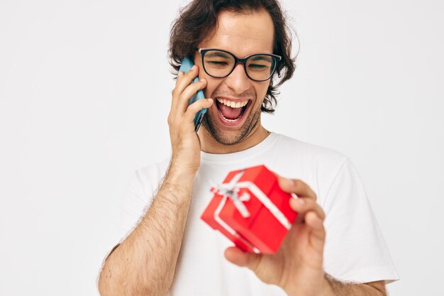 Fröhlicher Mann Rote Geschenkbox Telefonkommunikation heller Hintergrund