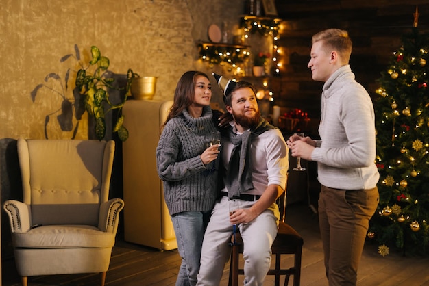 Fröhlicher Mann spricht mit Paar bei der Feier der Silvesterparty in einem dekorierten Raum
