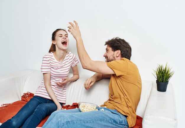 Fröhlicher Mann und Frau auf der Couch mit Popcorn und roter Plaid Blume in einem Topf Emotionen