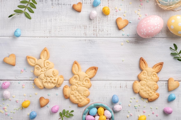 Fröhlicher Osterhintergrund mit Hasen, Eiern, Bonbons, Blumen