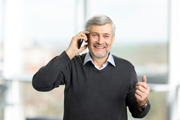 Foto fröhlicher reifer mann mit telefon. ein horizontales porträt des reifen mannes mit grauem haar und falten, die auf smartphone sprechen, verschwommen.