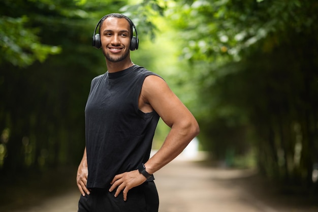 Fröhlicher schwarzer Athlet, der beim Joggen Musik hört, kopiert den Raum