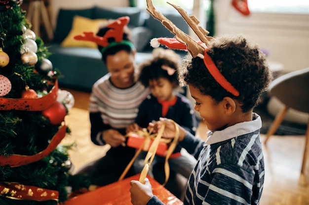 Fröhlicher schwarzer Junge, der mit seiner Familie zu Hause Weihnachtsvorbereitungen genießt