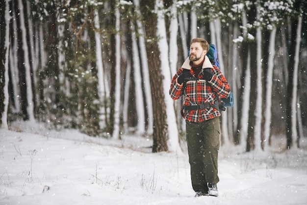 Fröhlicher Tourist, der aus dem Winterwald geht