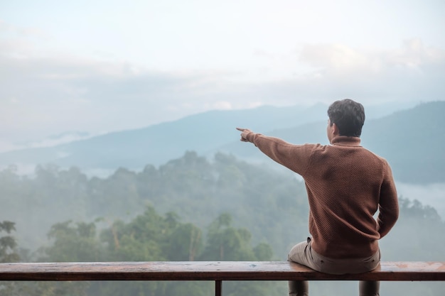 Fröhlicher Touristenmann, der sich morgens entspannt und Blick auf die Berge im Landhaus oder in der Gastfamilie blickt Urlaubsblogger SoloTravel-Reisereise und entspannendes Konzept