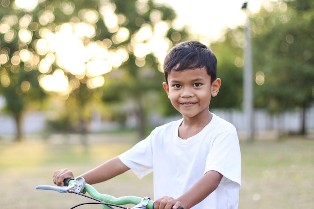 Fröhlicher und lächelnder Junge, der im Park Fahrrad fährt