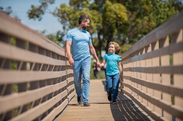 Fröhlicher Vater, der mit seinem Sohn im Freien spazieren geht, Freundschaft.