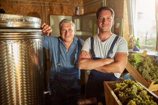 Fröhlicher Vater und Sohn stehen auf dem Weingut und schauen in die Kamera