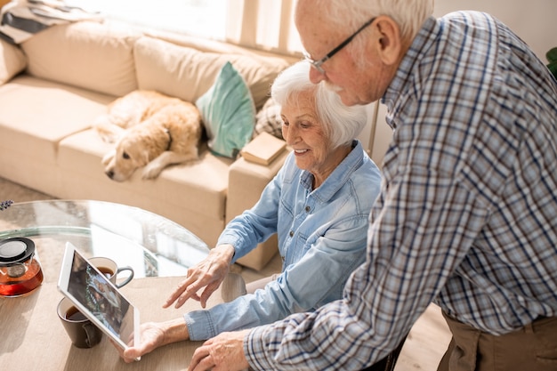 Fröhliches älteres Paar mit digitalem Tablet