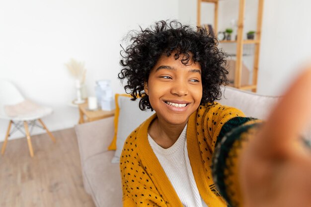 Fröhliches afrikanisch-amerikanisches Teenager-Mädchen, Blogger, lächelndes Gesicht, das mit der Webcam spricht, die Vlog aufzeichnet