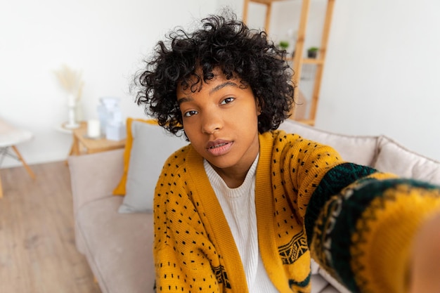 Fröhliches afrikanisch-amerikanisches Teenie-Bloggerin mit lächelndem Gesicht, das mit der Webcam-Aufzeichnung von Vlog Social Media spricht