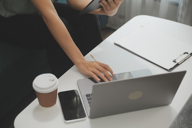 Fröhliches asiatisches Teenager-Mädchen hält ein Pad-Computergerät mit digitaler Tablet-Technologie in der Hand und sitzt zu Hause auf der Couch. Lächelnde junge Frau, die Apps nutzt, um online einzukaufen, Nachrichten zu lesen und auf dem Sofa im Internet zu surfen