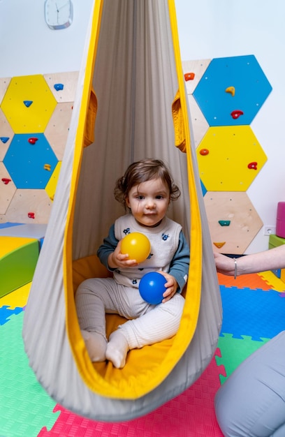 Fröhliches Baby, das Spaß mit bunten Bällen hat Entzückendes Kind, das auf dem bunten Spielplatz spielt