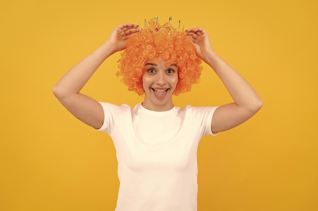 Foto fröhliches, egoistisches, lustiges mädchen mit ausgefallenem look, orangefarbener haarperücke und prinzessinnenkrone