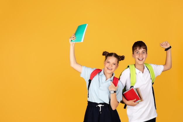 Fröhliches europäisches Teenager-Mädchen mit Rucksack Junge mit Notizbüchern feiern den Beginn des Studiums Erfolg