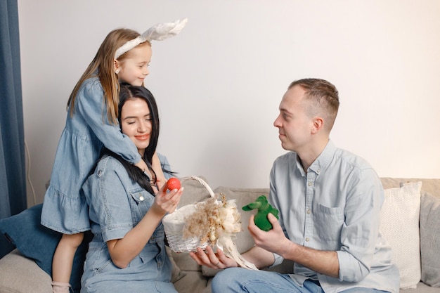 Fröhliches Familientreffen auf einer Couch im Wohnzimmer, das sich gemeinsam auf Ostereier vorbereitet