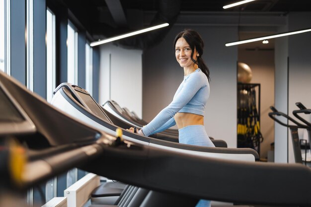 Fröhliches Fitness-Mädchen, das auf Laufband geht