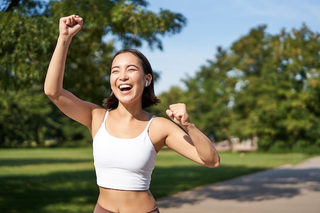 Fröhliches Fitness-Mädchen erreicht das Ziel beim Marathonlauf mit erhobenen Händen und feiert den Sieg beim Joggen