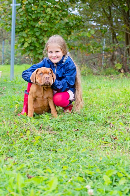 Fröhliches Foto eines Kindes und eines Welpen der Bordeauxdogge und seines kleinen Herrchens