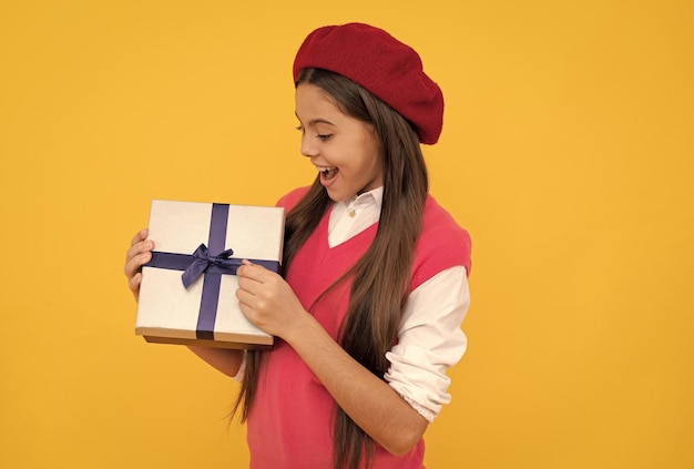 Fröhliches französisches Teenager-Mädchen öffnet Geschenkbox Kindheit Glück Boxing Day fröhliches Kind in Baskenmütze