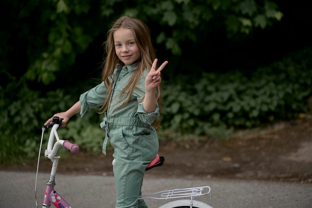 Foto fröhliches, fröhliches kindermädchen, das im park in der natur fahrrad fährt