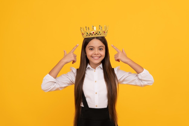 Fröhliches, fröhliches, selbstsüchtiges Teenager-Mädchen in Schuluniform trägt Prinzessinnenkronenarroganz