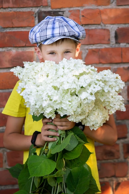 Fröhliches glückliches Dorfkind mit einem Blumenstrauß