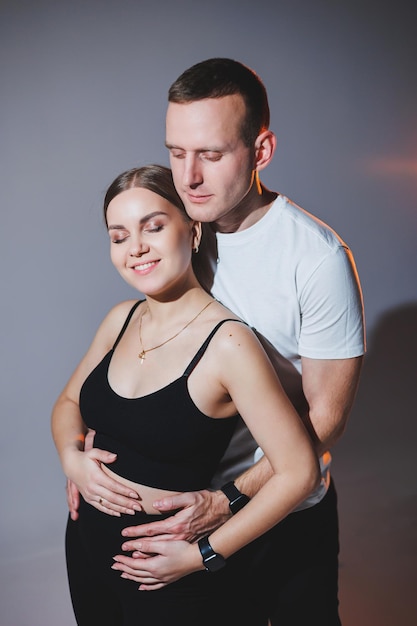 Fröhliches, glückliches junges paar, das sich auf einem einfachen hintergrund umarmt ein stilvoller mann und eine verliebte frau umarmen sich zärtlich