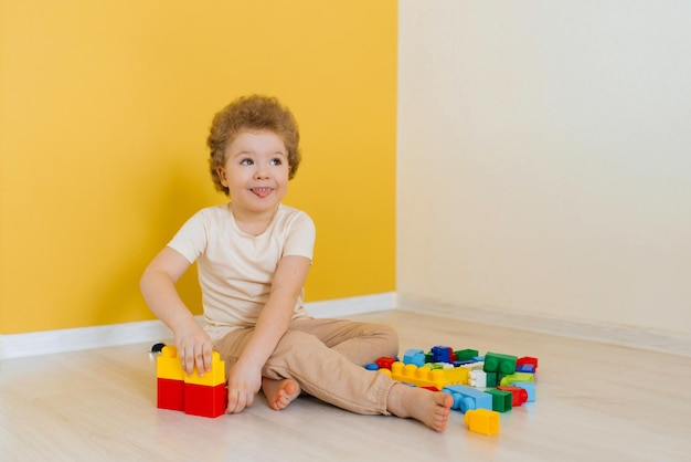 Fröhliches glückliches Kind spielt mit Spielzeug Ein Junge baut zu Hause einen Bausatz und verbringt Zeit damit