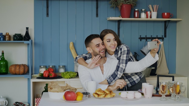 Fröhliches glückliches Paar beim Online-Video-Chat mit dem Smartphone in der Küche zu Hause