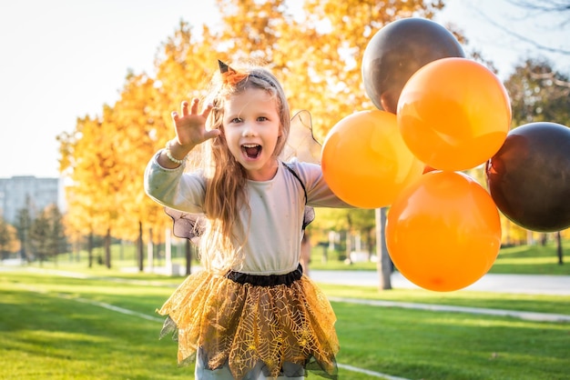 Fröhliches Halloween Süße kleine Hexe mit einem Luftball junges Mädchen im Hexenkostüm im Freien