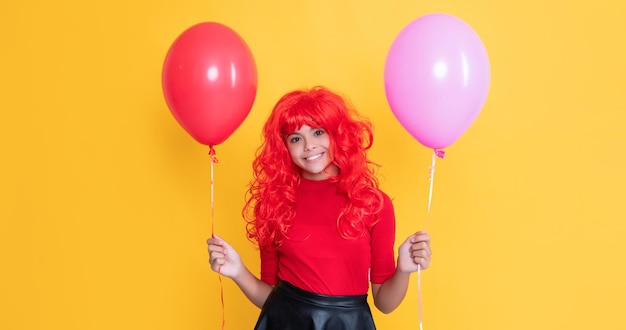 Fröhliches jugendlich Kind mit Partyballon auf gelbem Hintergrund