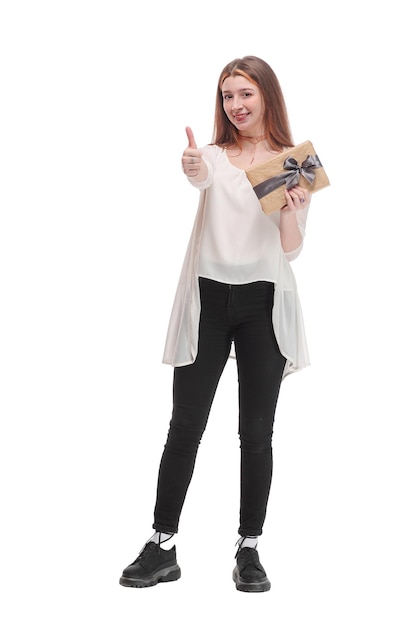 Fröhliches junges brünettes Mädchen, das eine Geschenkbox hält, die den Daumen nach oben zeigt, posiert isoliert auf weißem Hintergrund, Studioporträt. People-Lifestyle-Konzept.
