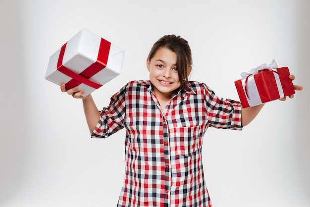 Fröhliches junges Mädchen, das mit zwei Geschenken aufwirft