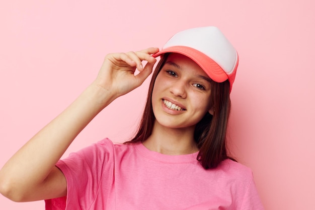 Fröhliches junges Mädchen mit einer Mütze auf dem Kopf in einem rosafarbenen T-Shirt