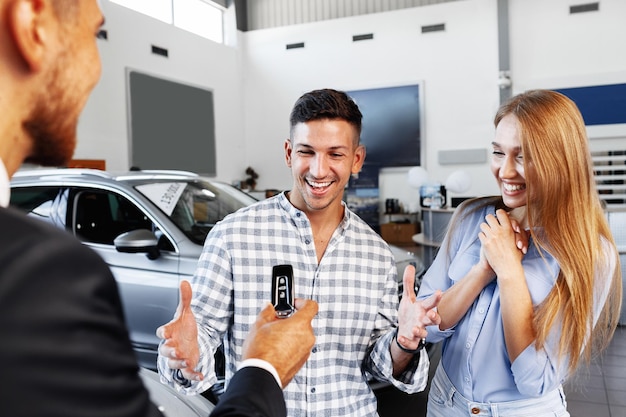 Fröhliches junges Paar beim Autokauf beim Kauf eines neuen Autos