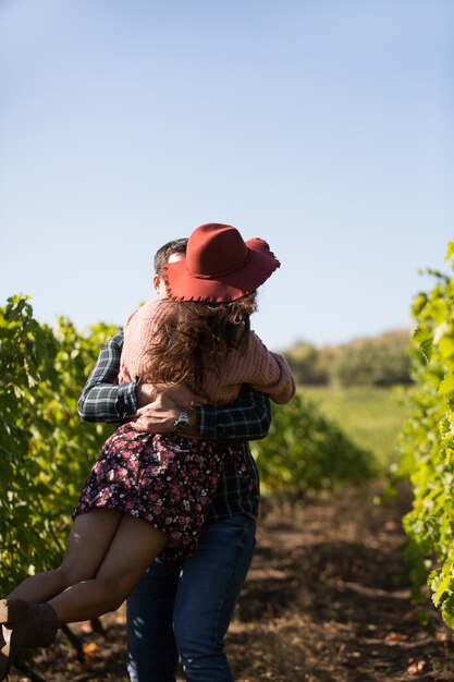 Fröhliches junges Paar, das einen romantischen Moment in einem Weinberg hat. Frau mit stilvollem Hut im Weinberg.