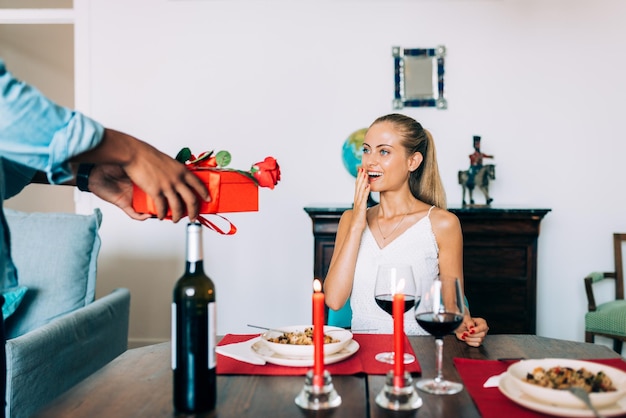 Fröhliches junges verliebtes gemischtrassiges Paar, das an einem romantischen Abendessen teilnimmt