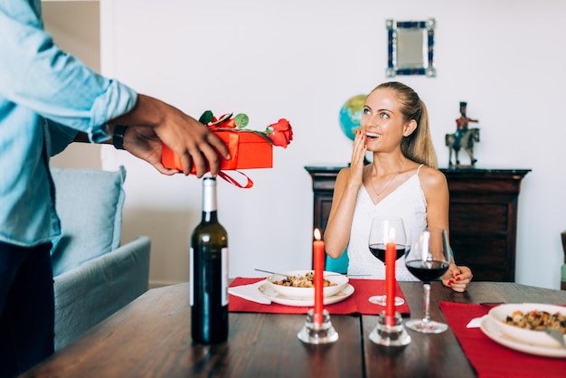 Fröhliches junges verliebtes gemischtrassiges Paar, das an einem romantischen Abendessen teilnimmt