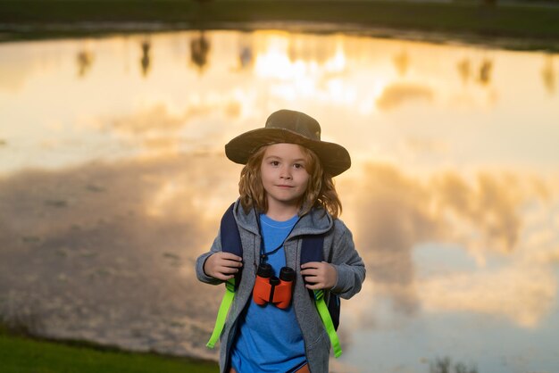 Fröhliches Kind, das mit dem Fernglas spielt Erkunden und Abenteuer Kind Junge mit Rucksäcken, die die Natur erkunden