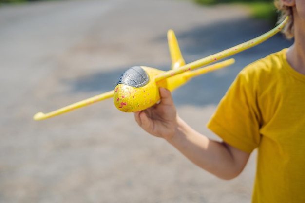 Fröhliches Kind, das mit Spielzeugflugzeug vor altem Start- und Landebahnhintergrund spielt Reisen mit Kinderkonzept