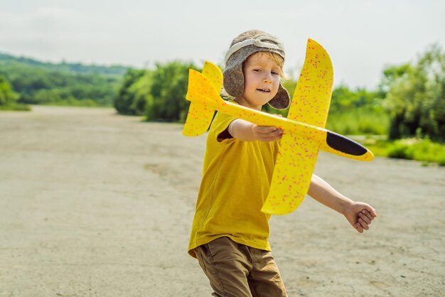 Fröhliches Kind, das mit Spielzeugflugzeug vor altem Start- und Landebahnhintergrund spielt Reisen mit Kinderkonzept